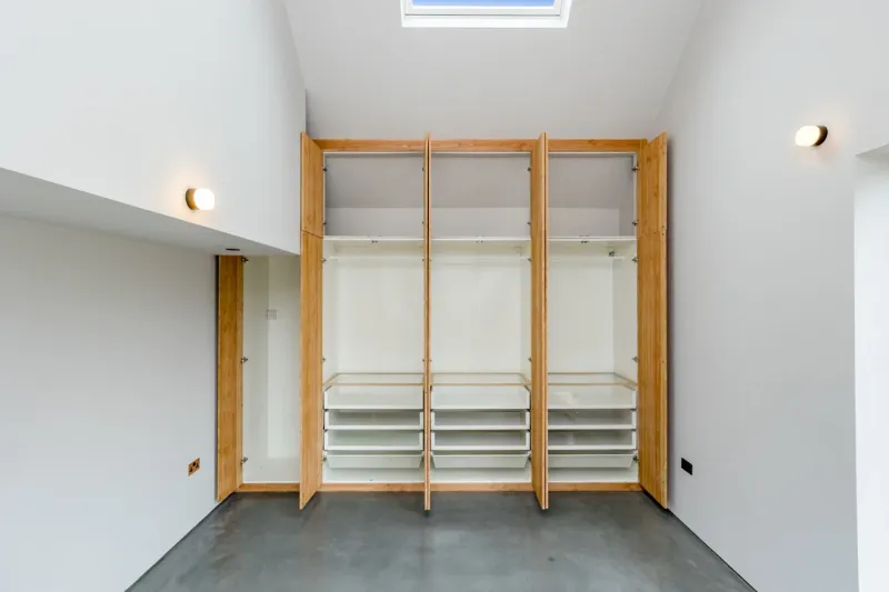 A run of tall built-in wardrobes with timber doors standing open