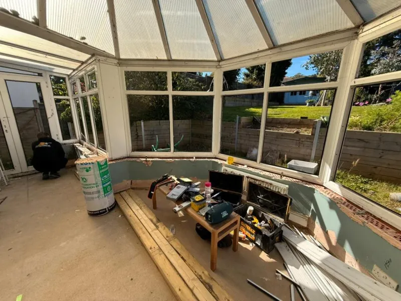 The old conservatory stripped out at the start of the build, with timber, insulation and tools on the floor.