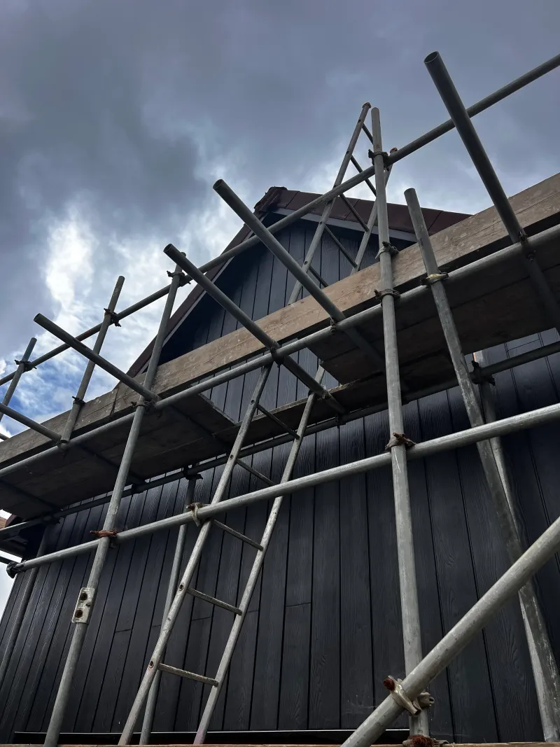 Black cladding going on the studio's gable behind scaffolding