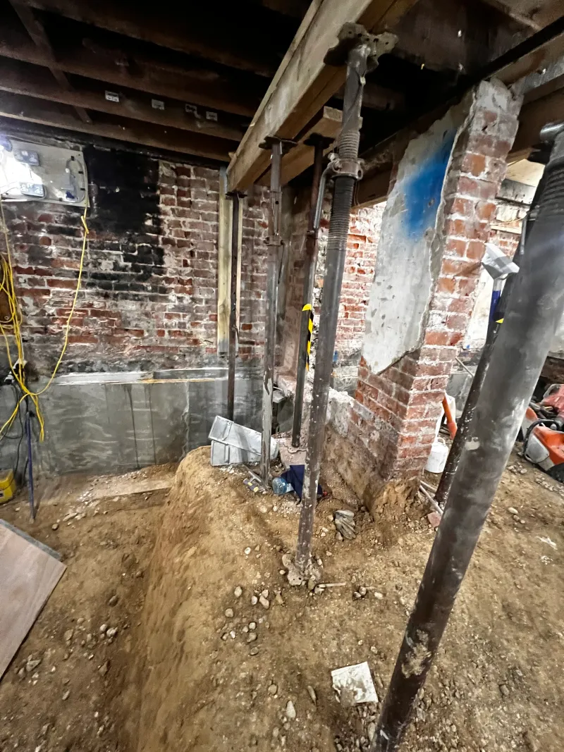Steel props holding up the floor above while the basement walls are underpinned