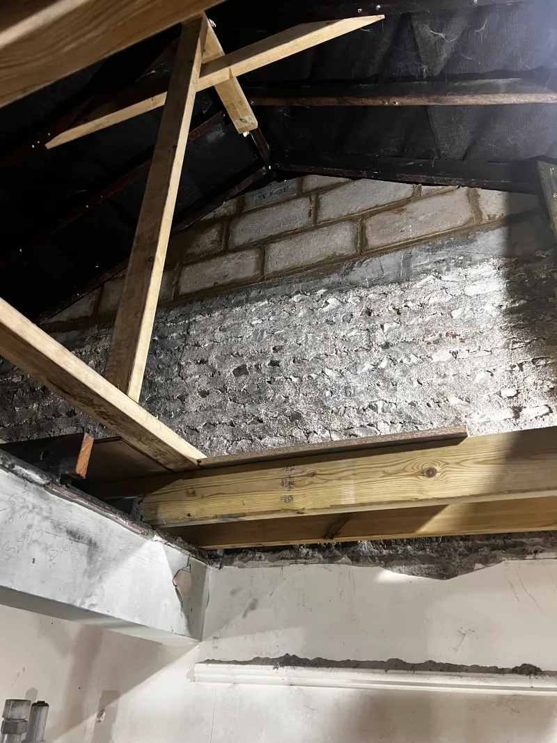 An old flint and rubble wall, exposed under new roof timbers