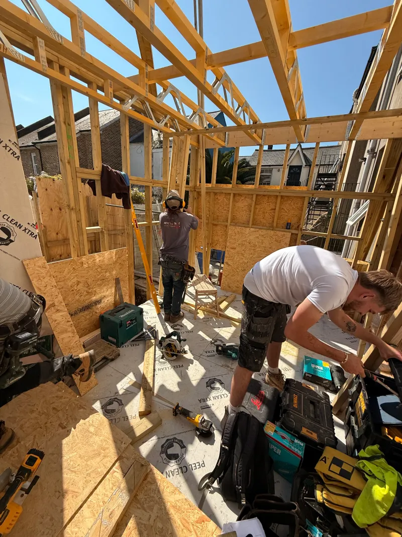 Carpenters raising the timber frame of the rear extension