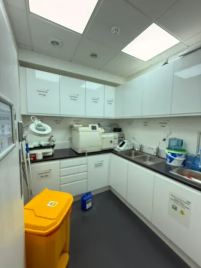 A fitted clinical decontamination room with sealed cabinetry, stainless sinks and a suspended LED ceiling.