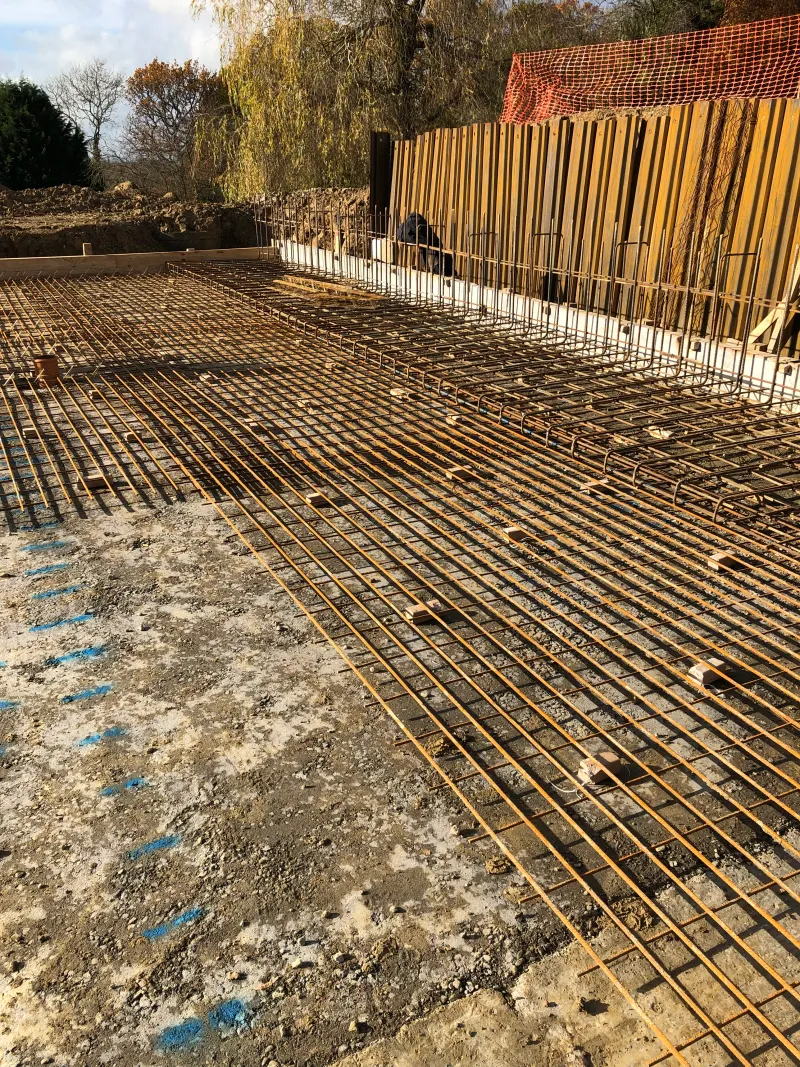 Steel reinforcement laid out for the ground slab, with sheet piling behind