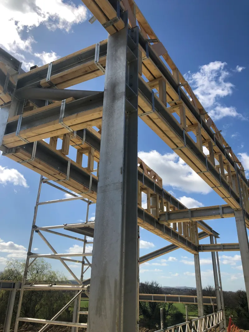 Steel posts and timber beams of the frame against a blue sky