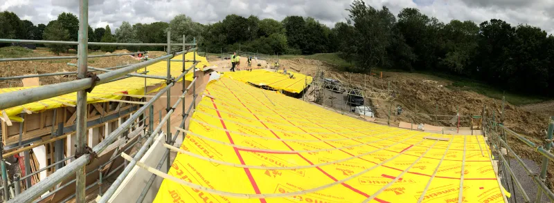 The roof deck from above, covered in yellow membrane, with fields beyond