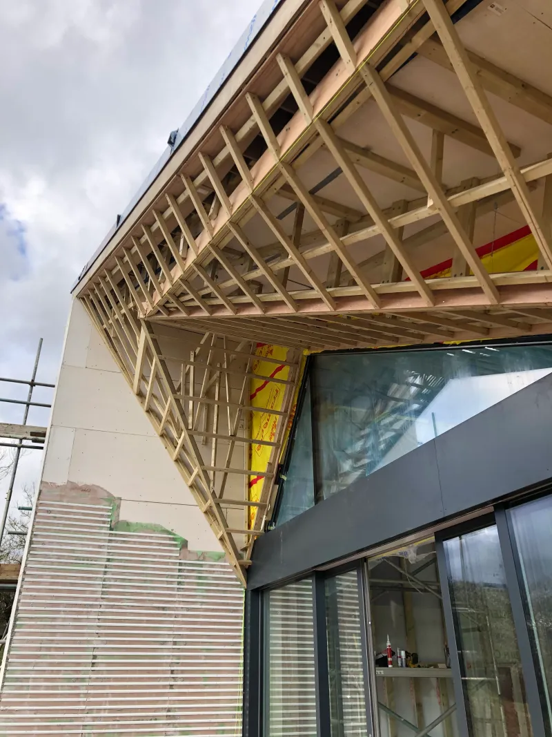 Timber framing for the folded roof overhang above the glazing, before its cedar lining