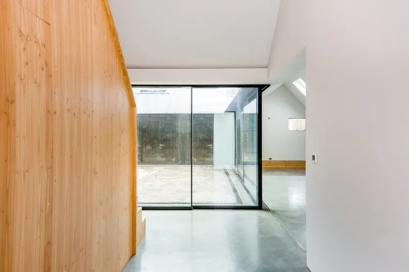 A contemporary extension interior with a timber-clad wall, polished concrete floor and sliding doors to a courtyard.