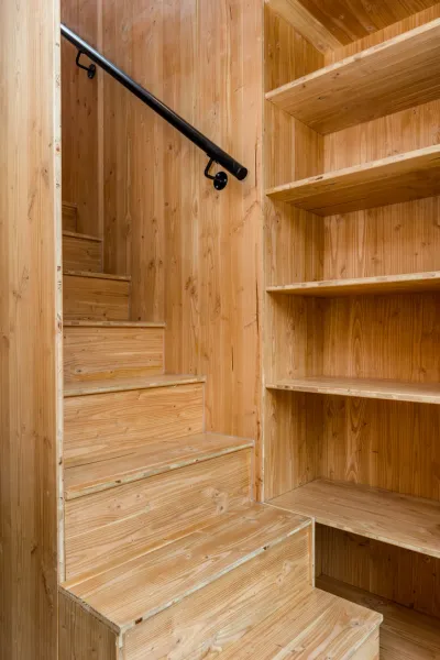 A bespoke pine staircase with integrated open shelving and a slim black handrail, from a Sussex modular and self-build project.